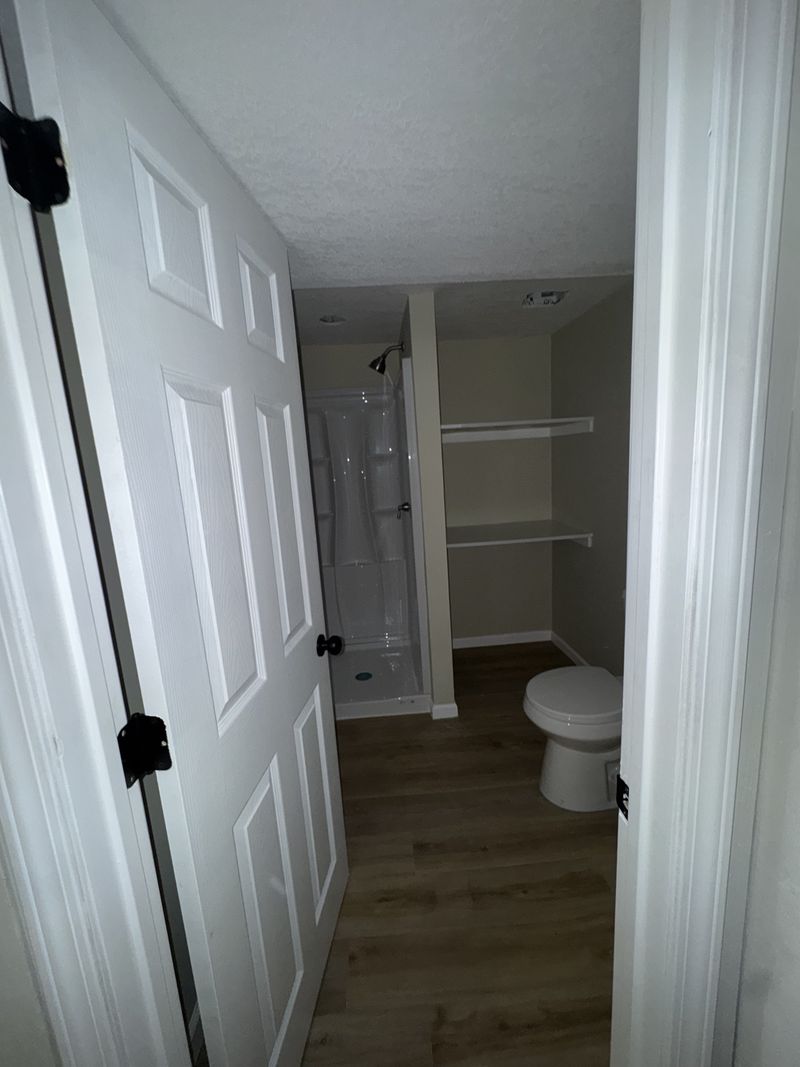Finished 3/4 bathroom with shower, toilet and shelving