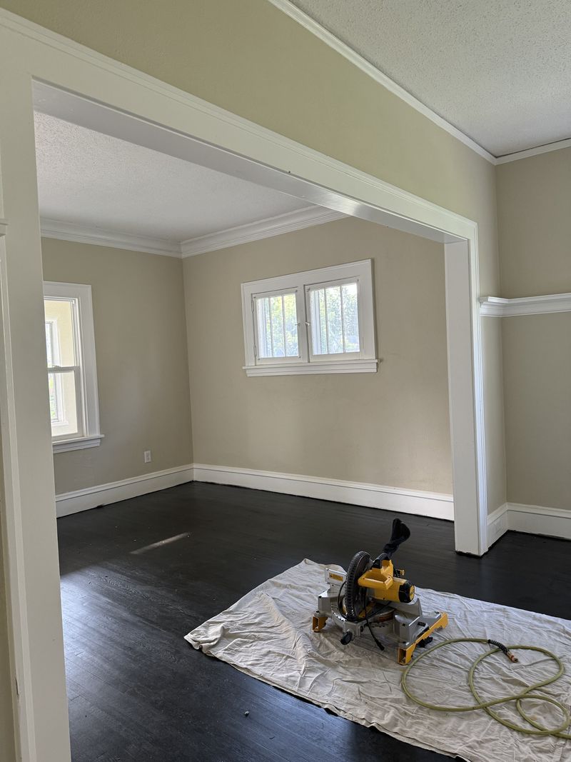 Room with white trim, casing and crown molding over dark floors
